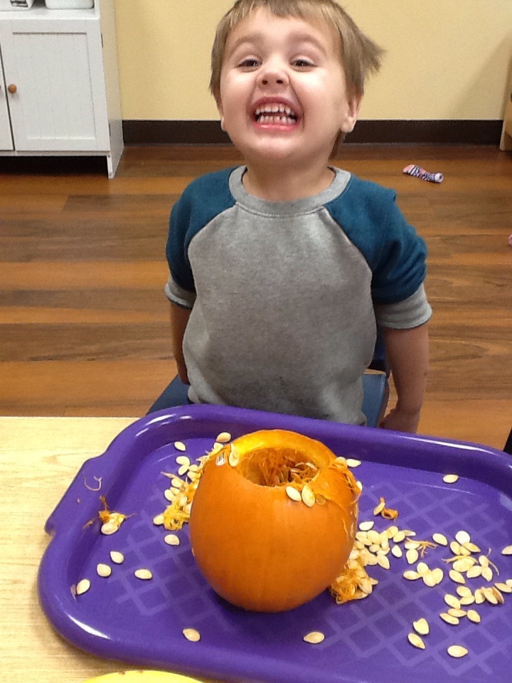 Henry is super smiling about pulling seeds from a pumpkin.